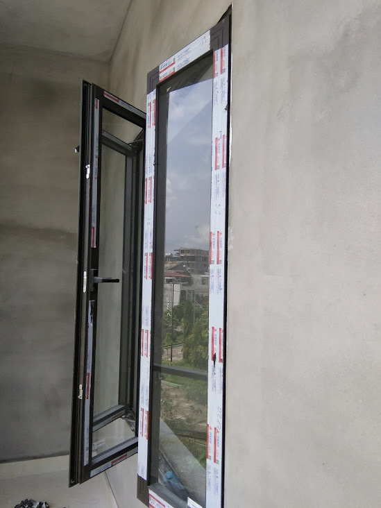 Cửa sổ nhôm kính mở quay màu đen mới lắp đặt trên tường bê tông nhìn ra ngoài trời